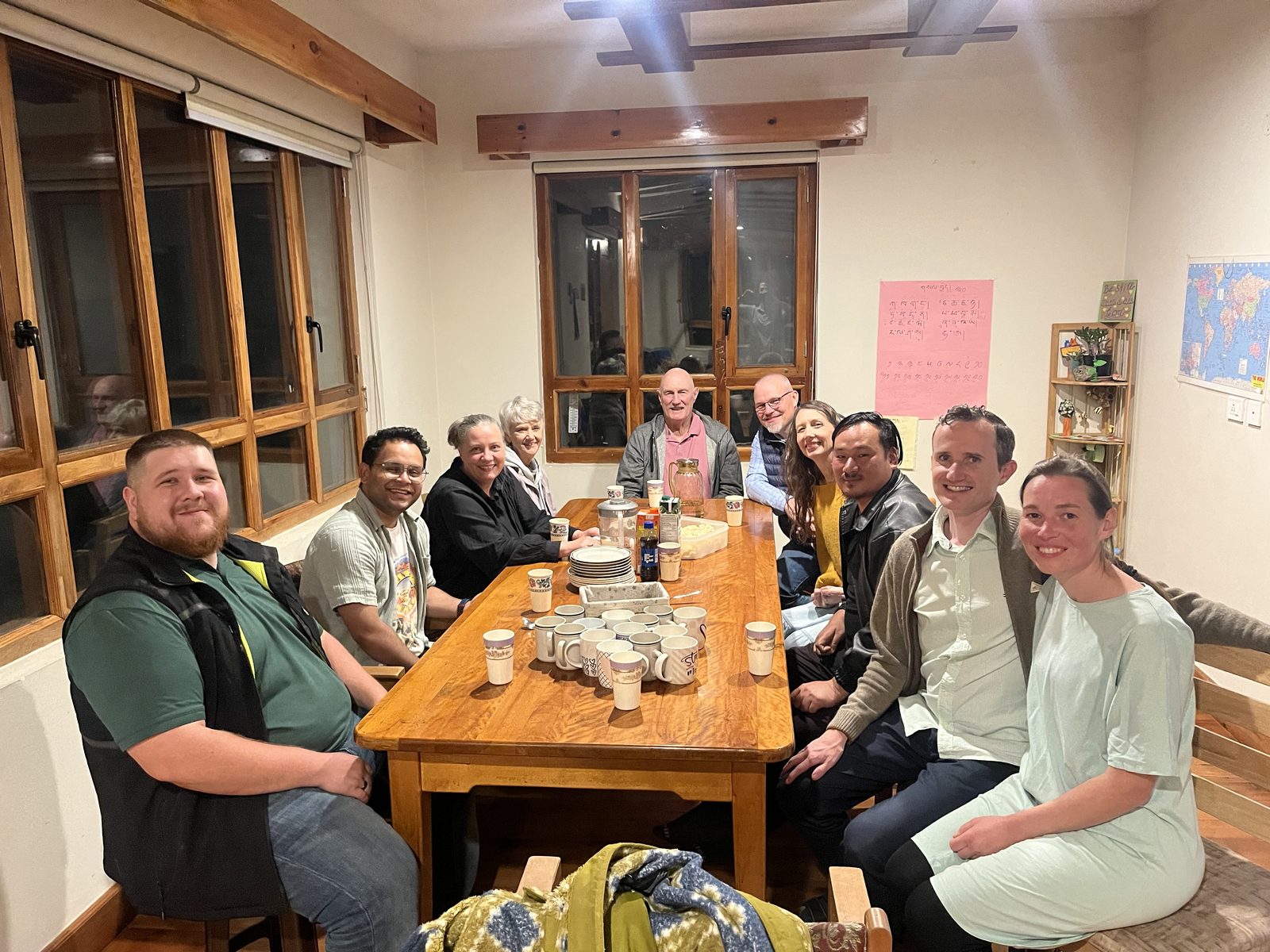 The Zampa team and Bhutanese friends around a long dinner table, smiling at the camera