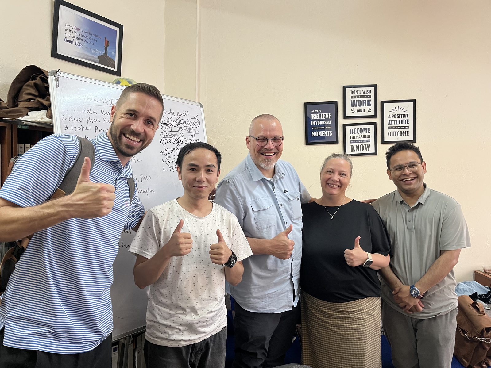 Zampa team members and Bhutanese colleagues giving a thumbs up in front of a whiteboard